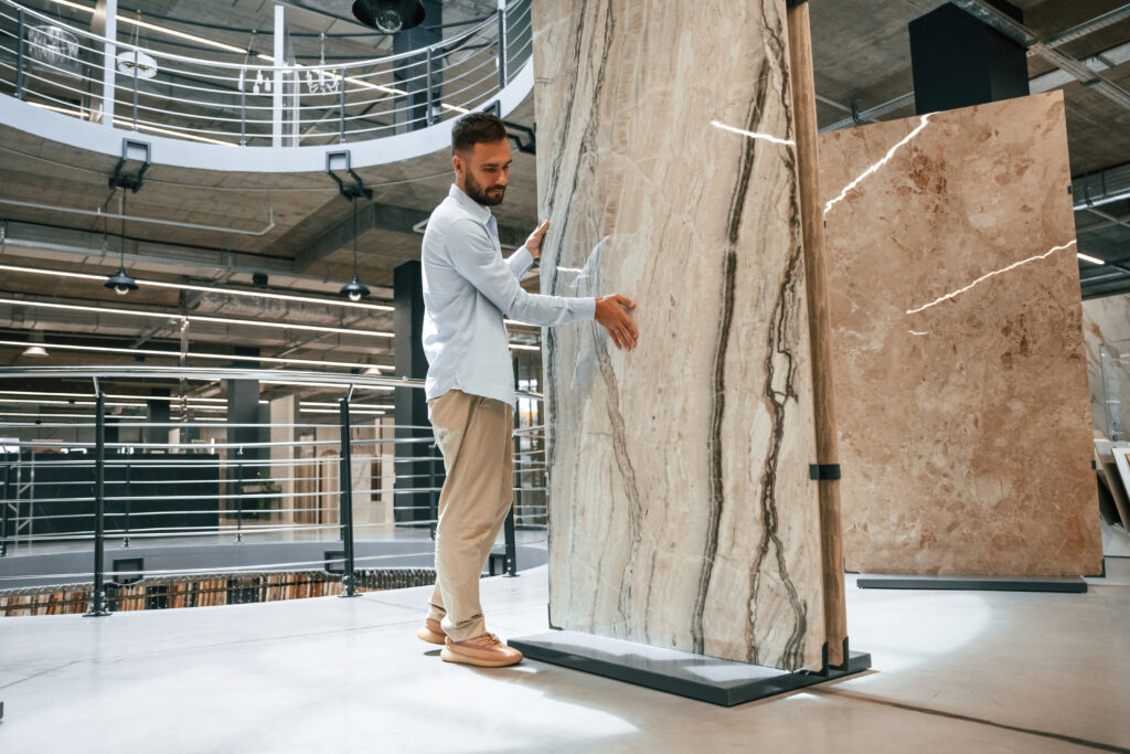Homme inspectant une grande dalle de marbre en magasin.